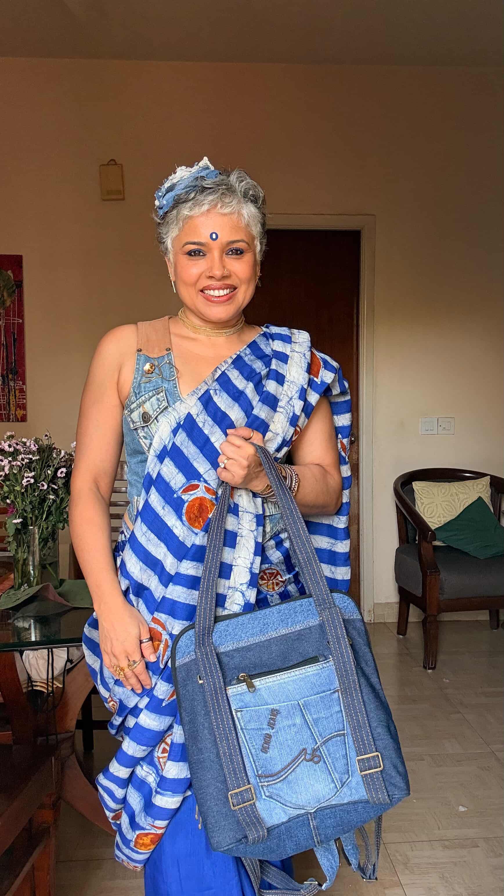 Woman styling the Born Again denim bag with a blue and white sari